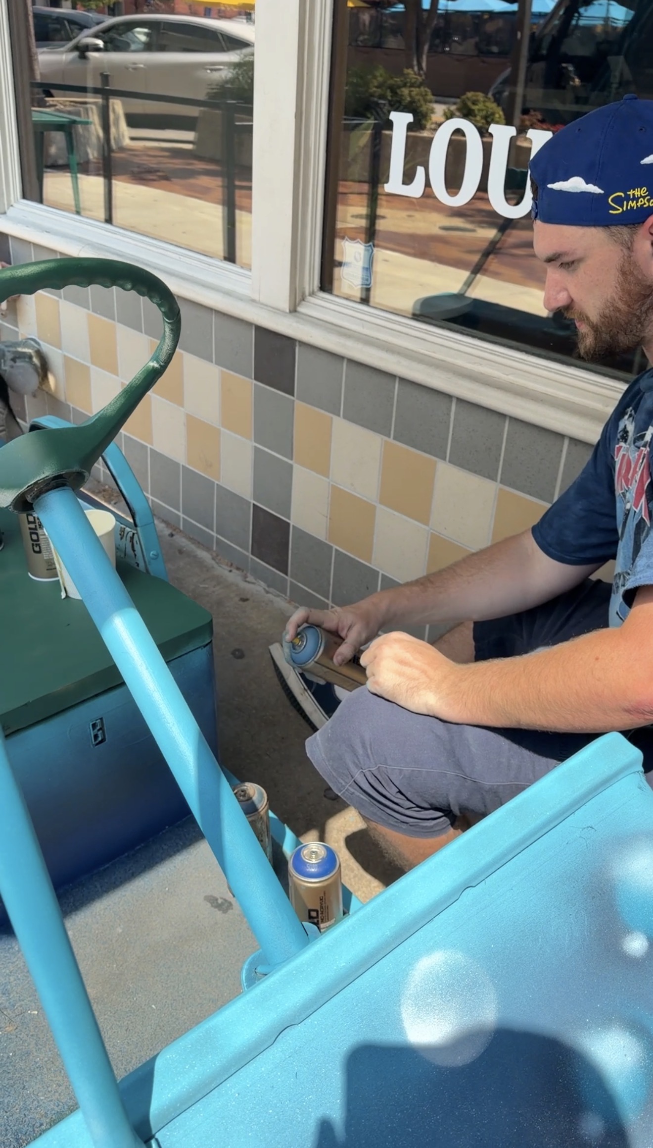 Travel Art Dad spray painting the golf cart out front of RECESS Lawrence