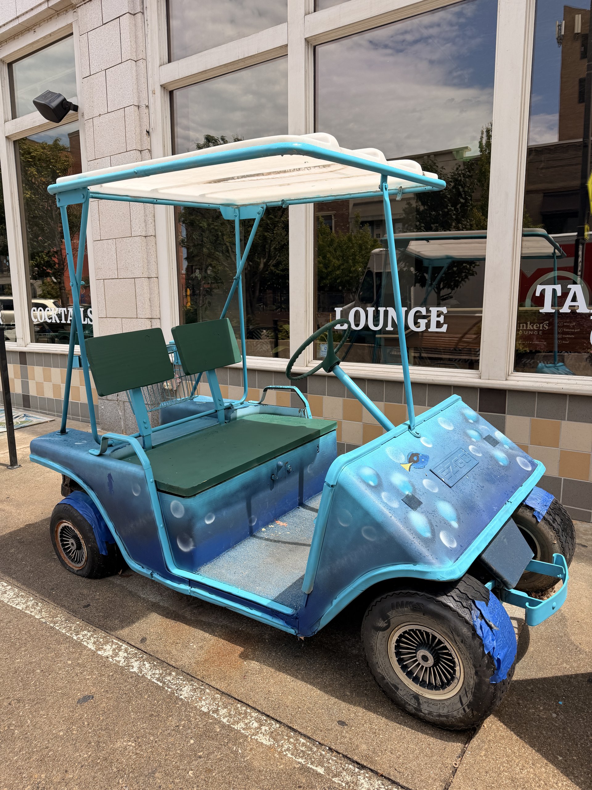 The current golf cart, painted in Finding Dory blues, parked out front of RECESS Lawrence